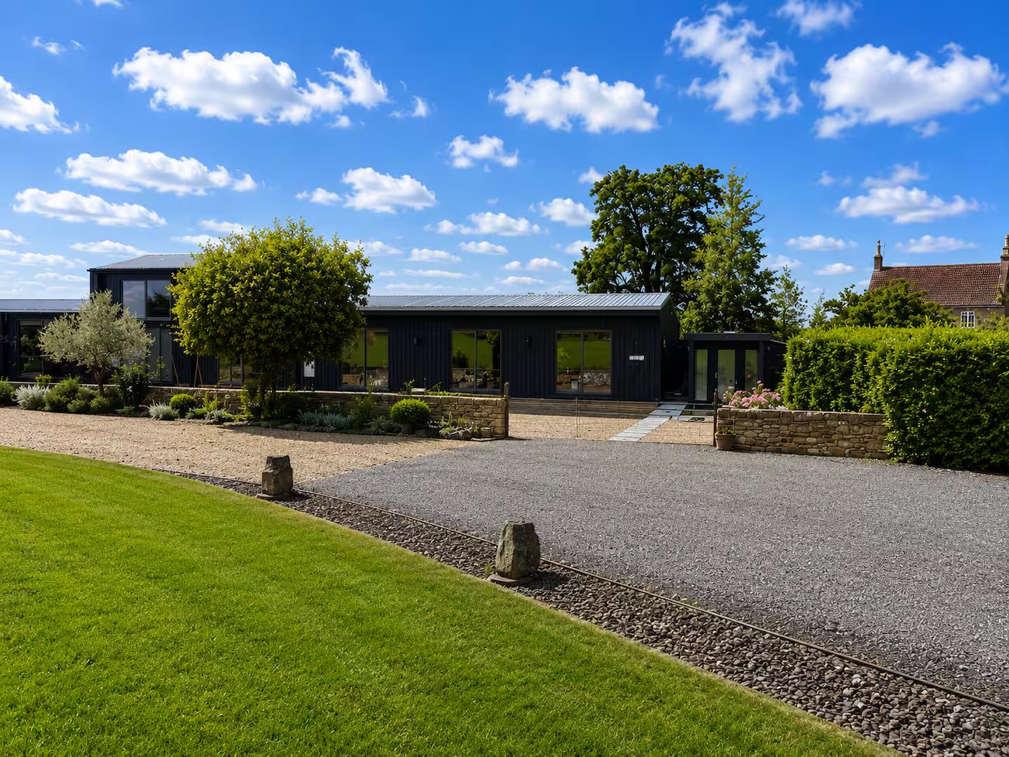 The black timber barn with gravel drive and gardens